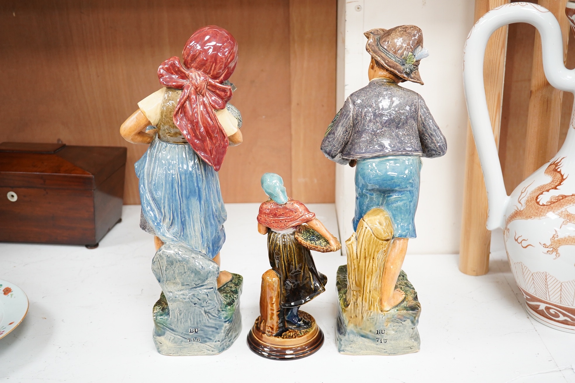 A pair of Austrian majolica figures of children, one holding a cat, the other a parrot, together with a similar smaller figure, tallest 37.5cm high (3). Condition - fair